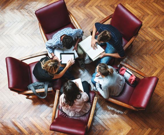 Image of students captured from above discussing seating on chairs